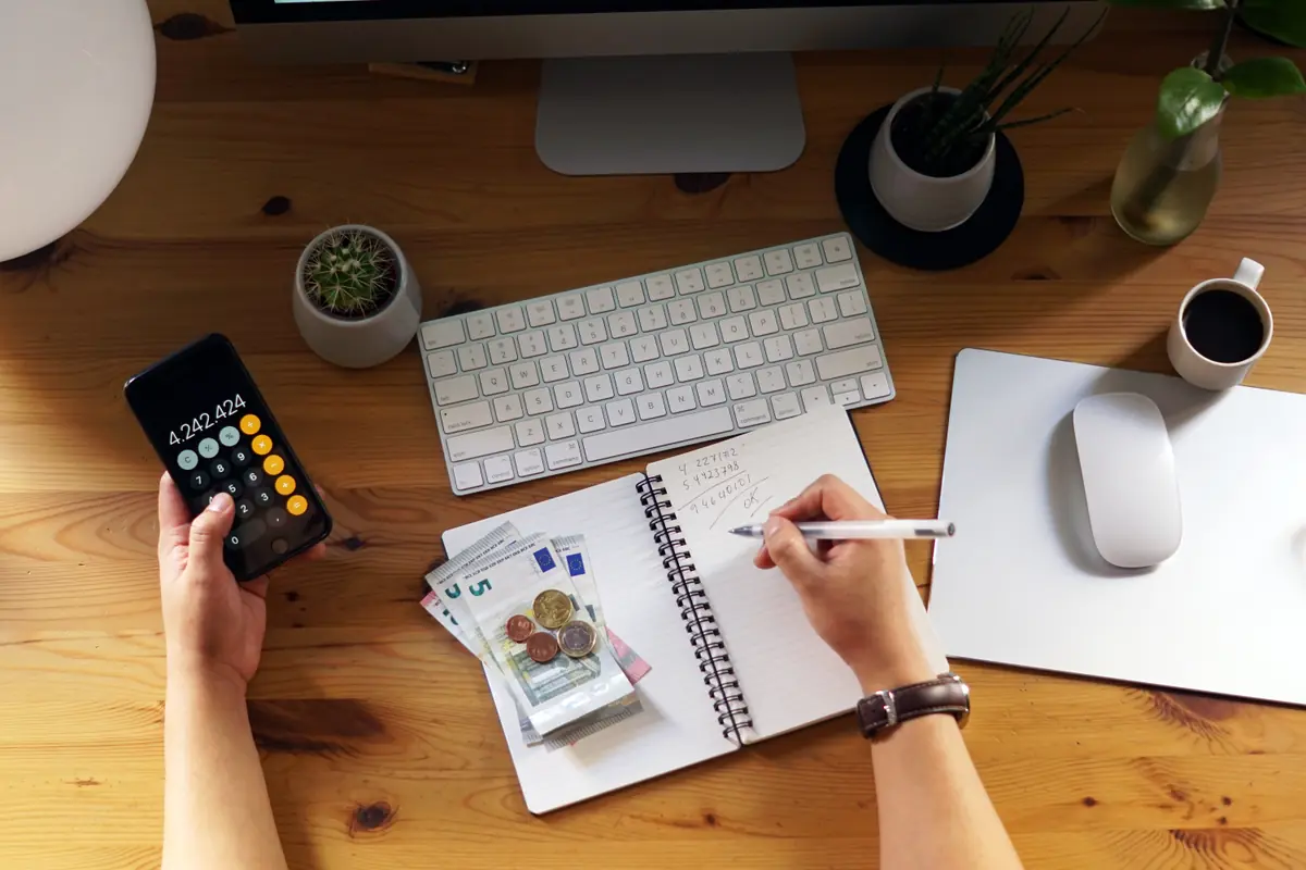 Hesap makinesi ve not defteriyle aylık Instagram reklam bütçesini hesaplayan girişimci
